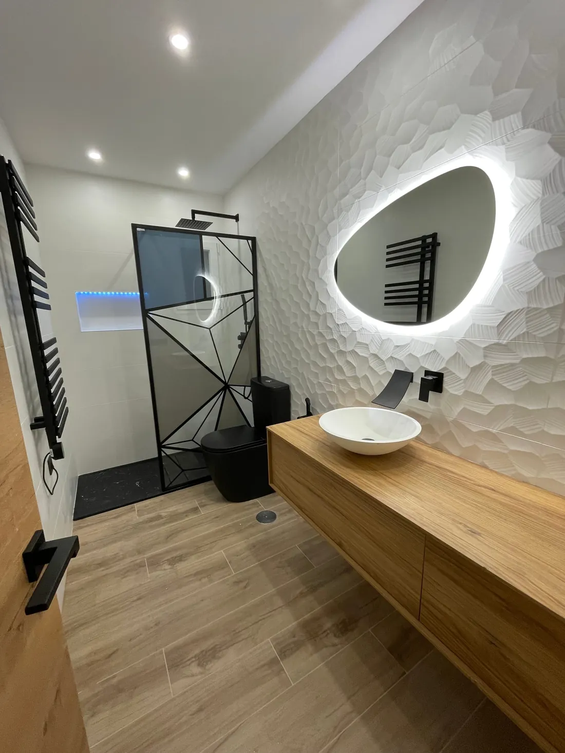 Baño Isis: mueble suspendido de madera, lavabo sobre encimera y espejo orgánico retroiluminado