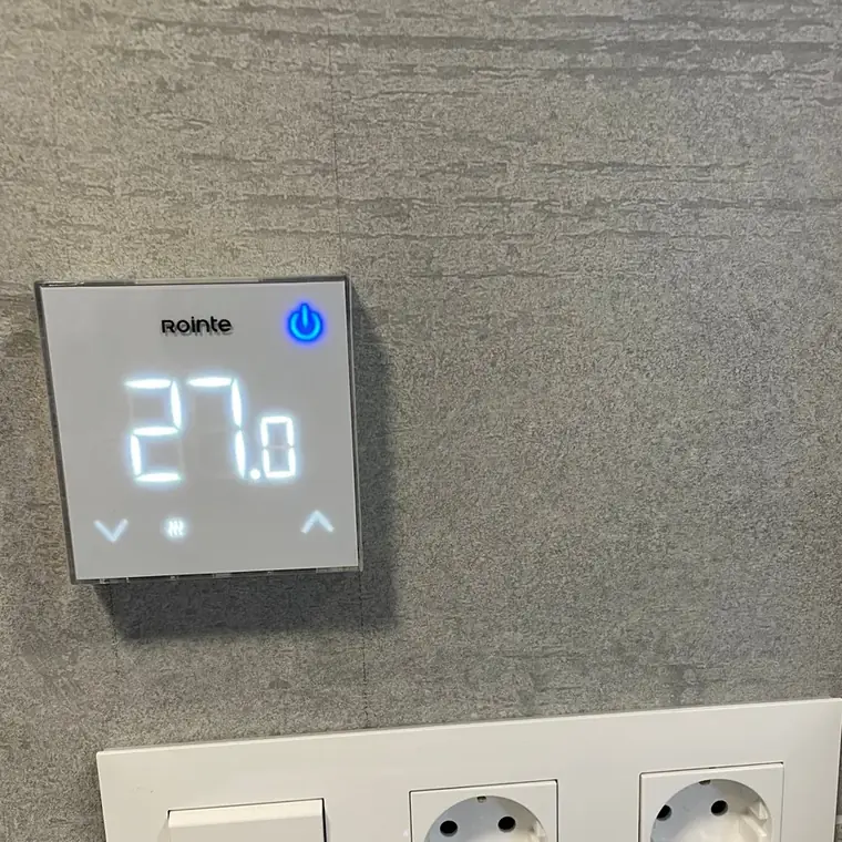 Termostato de suelo radiante marcando 27 grados en un baño terminado